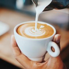 Person pouring milk into a cup of coffee