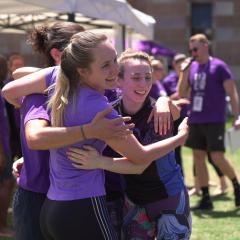 Three girls embracing each other at the Giving Day races on the Great Court
