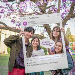 Students holding a Instagram post cut out and posing together with a sign reading "I completed a Student-Staff partnership".
