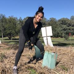 Female UQ student pressing a shovel into dried grass