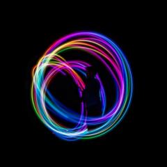 Long exposure of person swinging colour lights and creating a rainbow aura effect around themselves