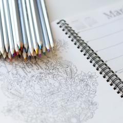 A stack of colouring pencils on a colouring book