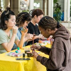 Students sitting at table painting pots.