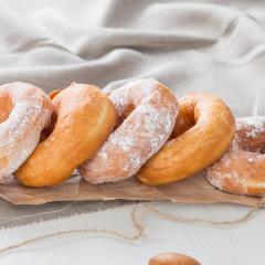 powdered and plain donuts on a wooden platter