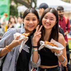 Two UQ students holding food a major event