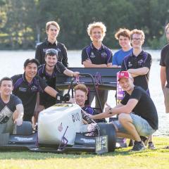 UQ racing team posing by their race car in front of UQ lakes