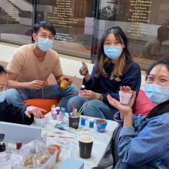 Group of students sitting around a table painting small pots for plants