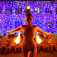 Fire dancer standing in front of 2021's Long Table Dinner set up with Forgan Smith lit up in white and purple lights