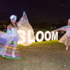 Fairy dancers in front of large light up "Bloom" sign