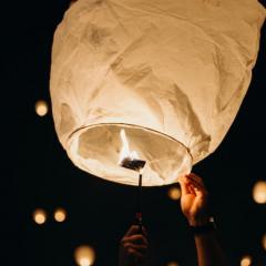 White lantern with small flame being released into the night sky