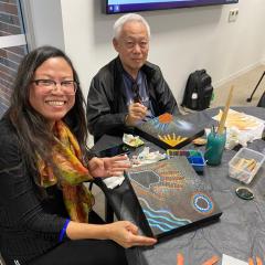 Two people holding up their artwork and enjoying the Indigenous Art workshop by Indigenous artist Ang Bennett 