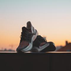pair of running shoes sitting on a ledge with a sunset in the background