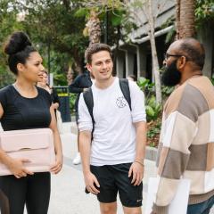 Three diverse students standing and talking at the St Lucia campus