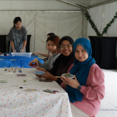 UQ students sitting at table and painting.