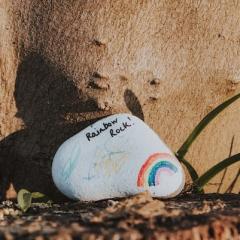 Small rock painted with a rainbow and the words "rainbow rock!"