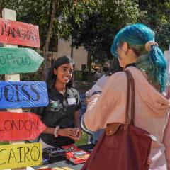Girl with blue hair chatting to female ambassador at wellbeing stall