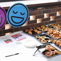Pastries displayed on table with corflute cut-outs of purple and blue smiley faces.