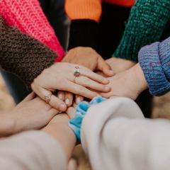 A group of diverse women layering their hands on top of each other